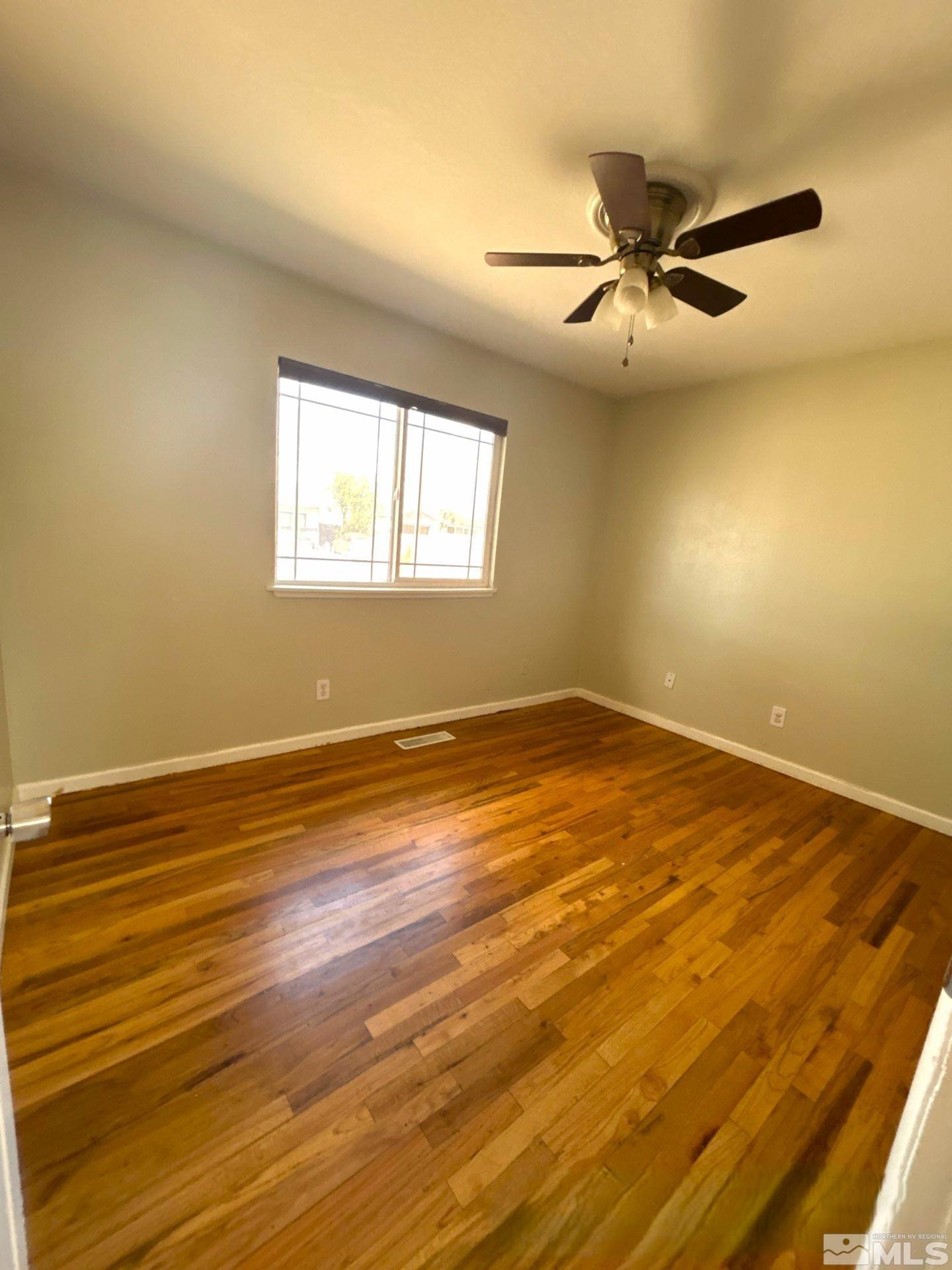 25 Comstock Drive Fernley, NV 89408 - Photo 5 of 10 an empty room with wooden floor and windows