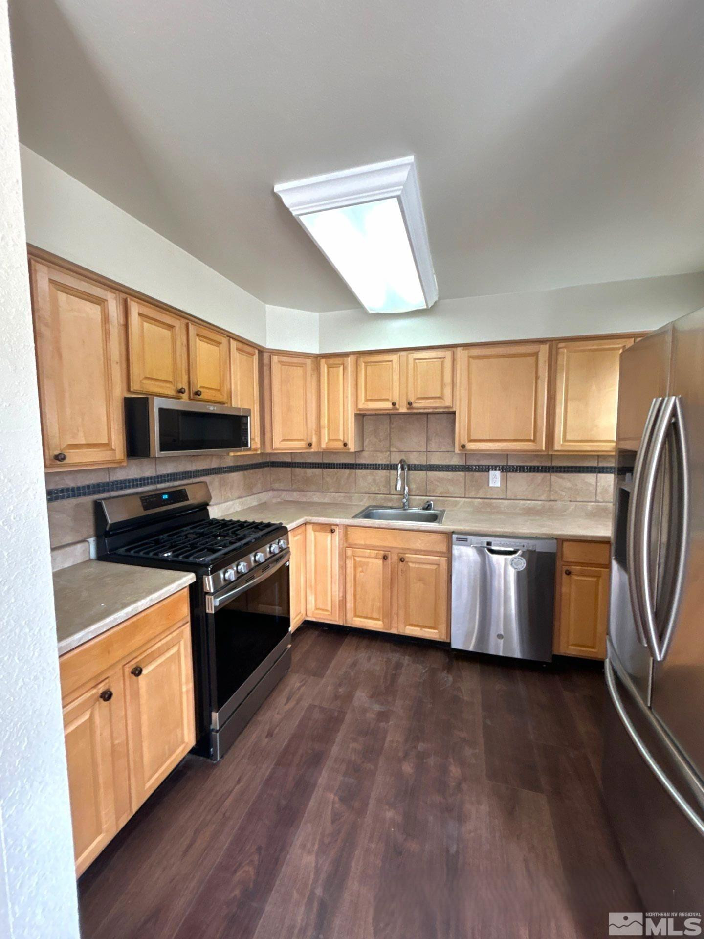25 Comstock Drive Fernley, NV 89408 - Photo 6 of 10 a large kitchen with stainless steel appliances granite countertop a stove a sink dishwasher and white cabinets with wooden floor