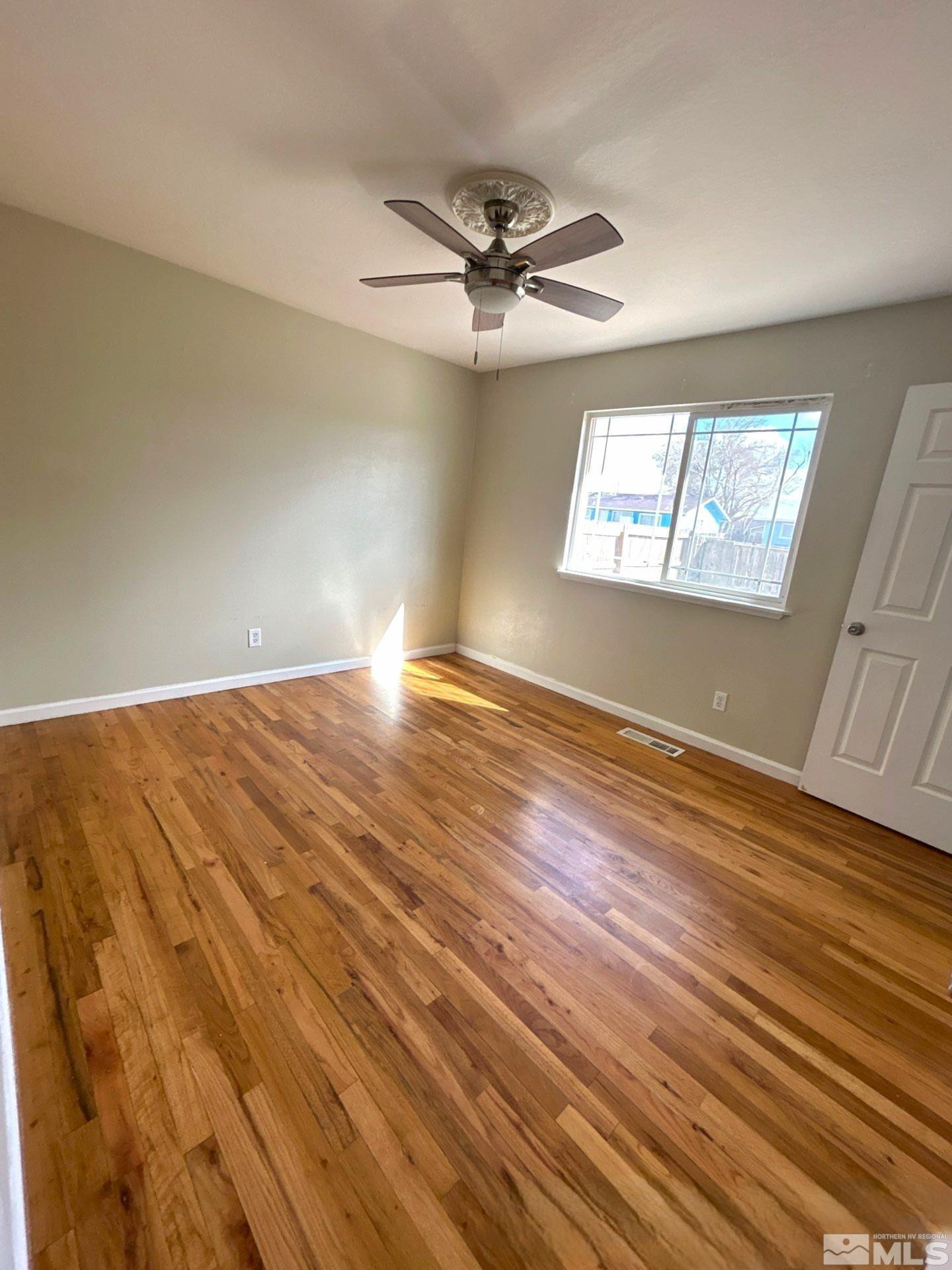 25 Comstock Drive Fernley, NV 89408 - Photo 10 of 10 an empty room with wooden floor fan and windows