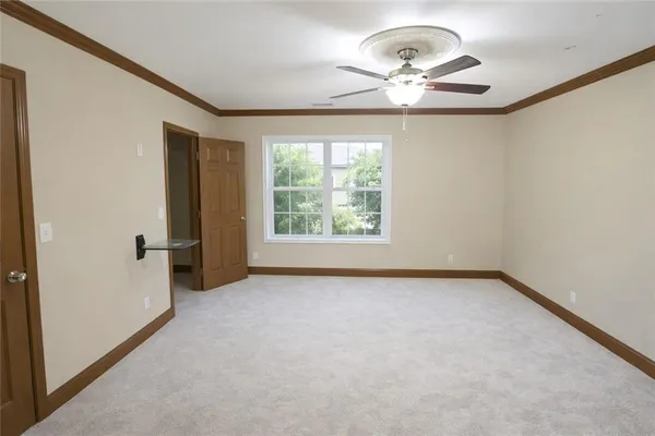 an empty room with windows and chandelier fan