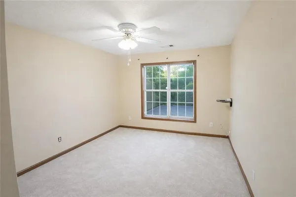 an empty room with windows and fan