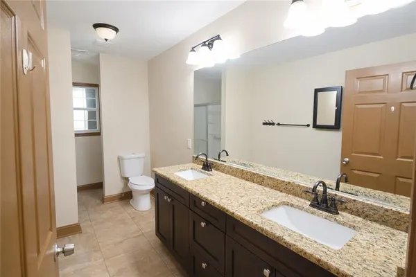 a bathroom with a granite countertop sink a toilet and shower