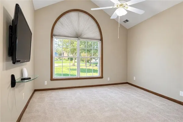 an empty room with windows fireplace and fan