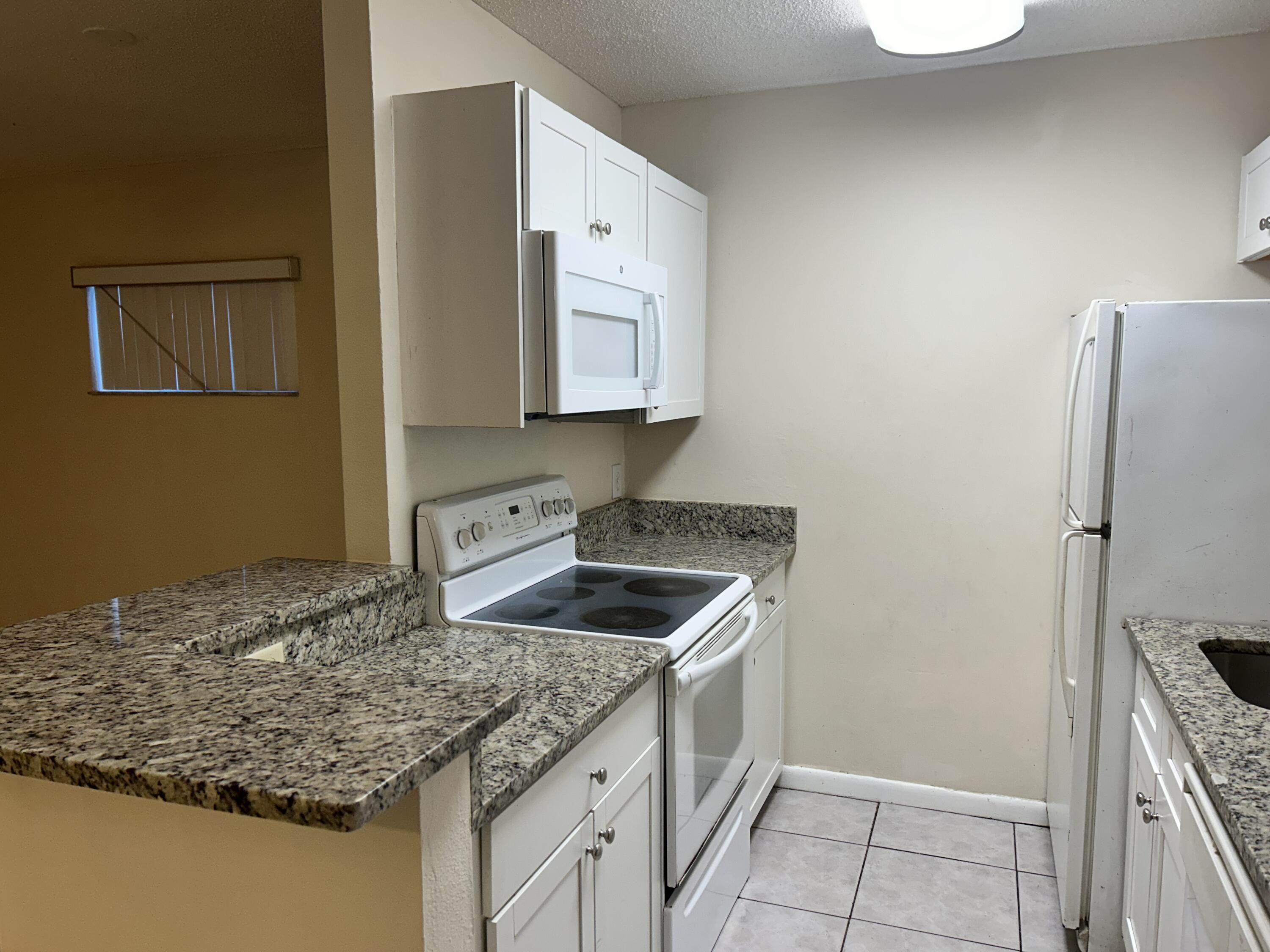 23 Crossings Circle, Unit E Boynton Beach, FL 33435 - Photo 6 of 19 a kitchen with stainless steel appliances granite countertop a sink stove and refrigerator