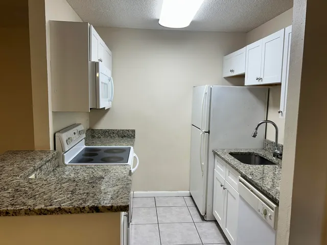 a kitchen with granite countertop a sink stove and refrigerator