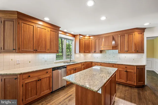 a kitchen with stainless steel appliances granite countertop a refrigerator a sink dishwasher a stove and white countertops with wooden floor