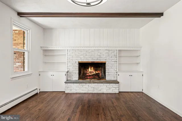 an empty room with wooden floor fireplace and windows