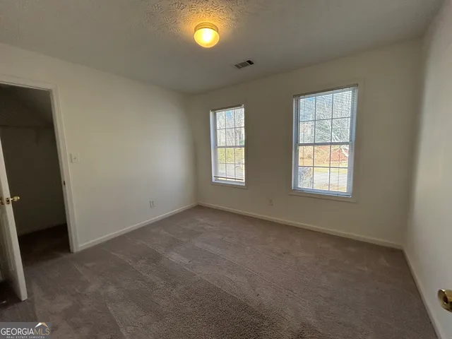 an empty room with windows and fan