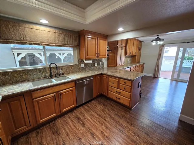a kitchen with stainless steel appliances granite countertop wooden floors wooden cabinets and sink