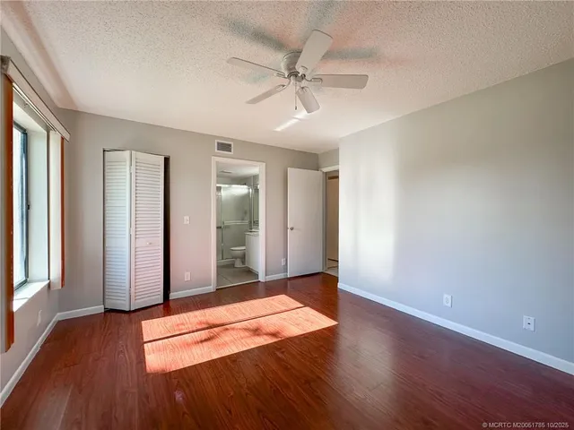 an empty room with wooden floor chandelier fan and windows
