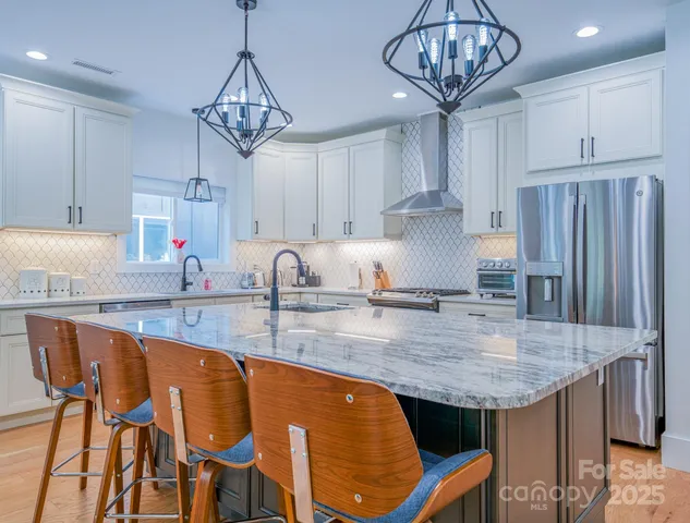 a kitchen with stainless steel appliances granite countertop a sink a stove and a refrigerator