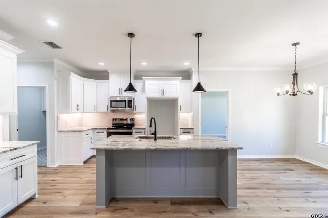 a kitchen with stainless steel appliances granite countertop a sink a stove and a wooden floor