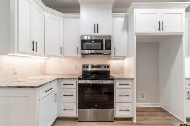 a kitchen with stainless steel appliances granite countertop a sink a stove and a wooden floors