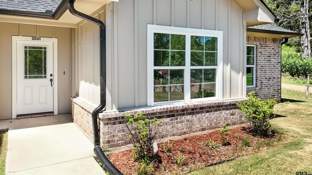 an empty room with wooden floor ceiling fan and windows
