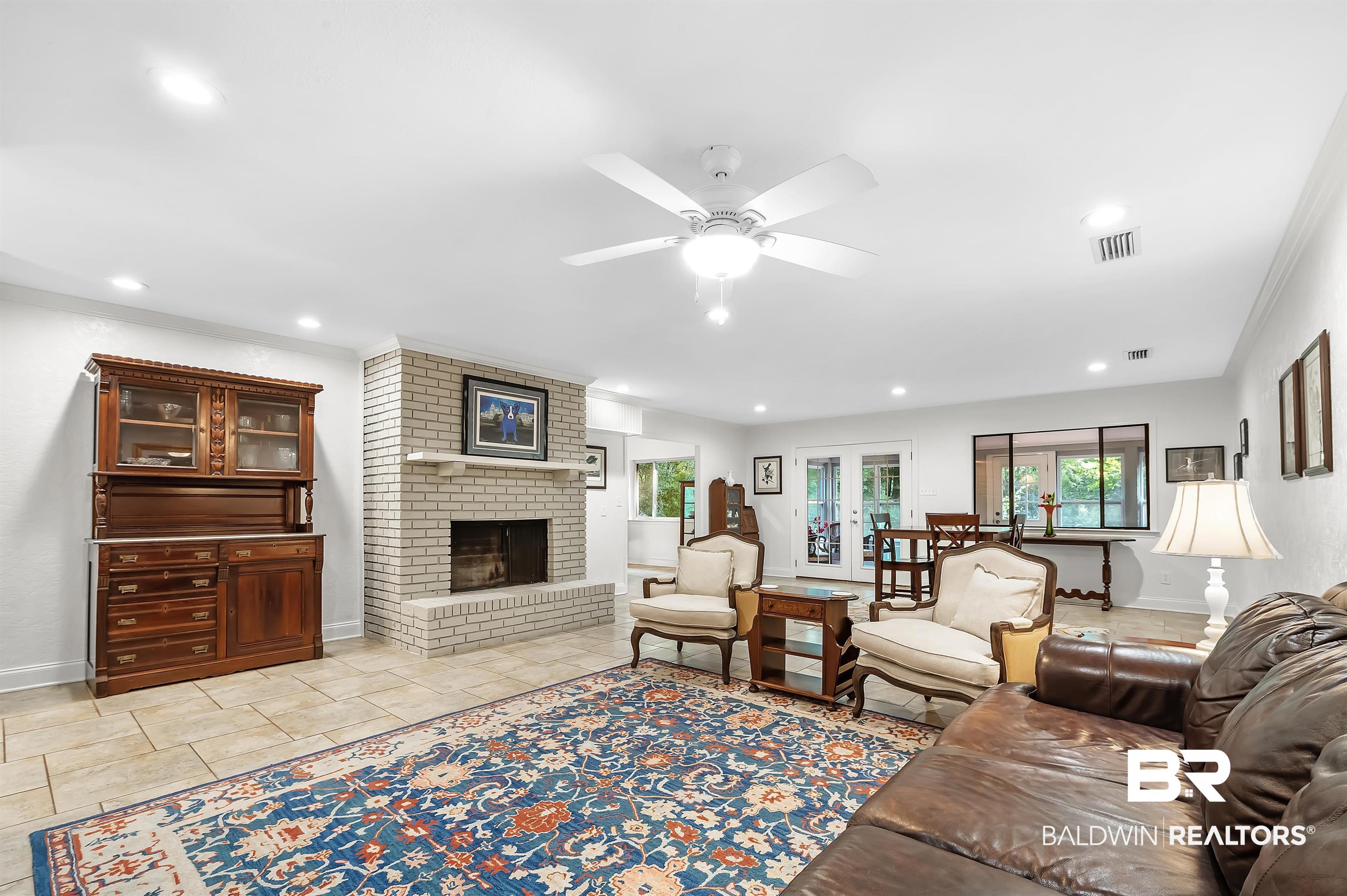 104 James Circle Daphne, AL 36526 - Photo 25 of 62 Living room with a fireplace, light tile patterned floors, crown molding, brick wall, and ceiling fan