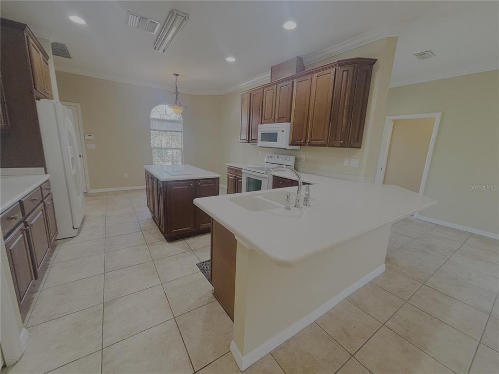 4940 Southwest 63rd Loop Ocala, FL 34474 - Photo 7 of 45 a kitchen with stainless steel appliances a sink a stove a microwave a counter top space and cabinets