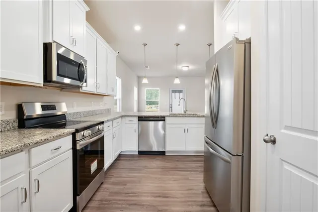 a kitchen with stainless steel appliances granite countertop a refrigerator a stove top oven a sink and dishwasher