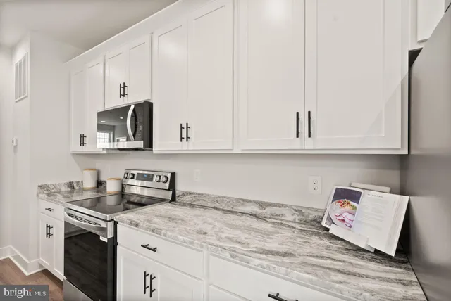 a kitchen with stainless steel appliances granite countertop white cabinets and sink