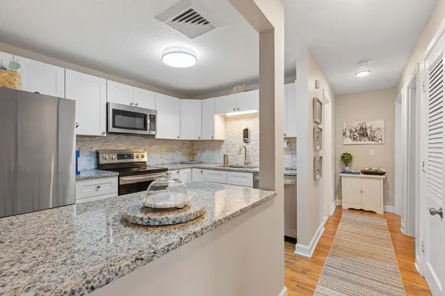 a kitchen with stainless steel appliances granite countertop a sink stove refrigerator and cabinets