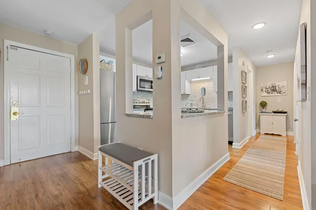 a view of a hallway with wooden floor and a bathroom