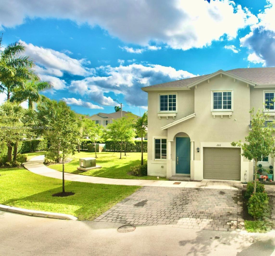 a view of a house with a big yard plants and large tree