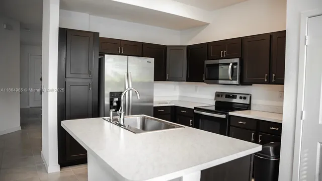 a kitchen with a refrigerator a sink a stove a microwave and wooden cabinets