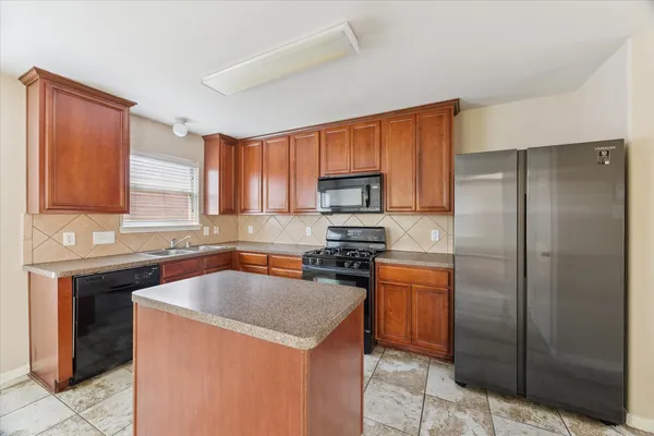 a kitchen with stainless steel appliances granite countertop a sink stove refrigerator and cabinets