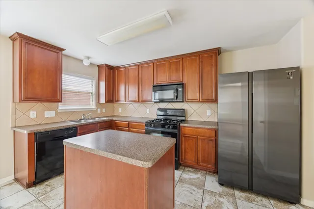 a kitchen with stainless steel appliances granite countertop a sink stove refrigerator and cabinets