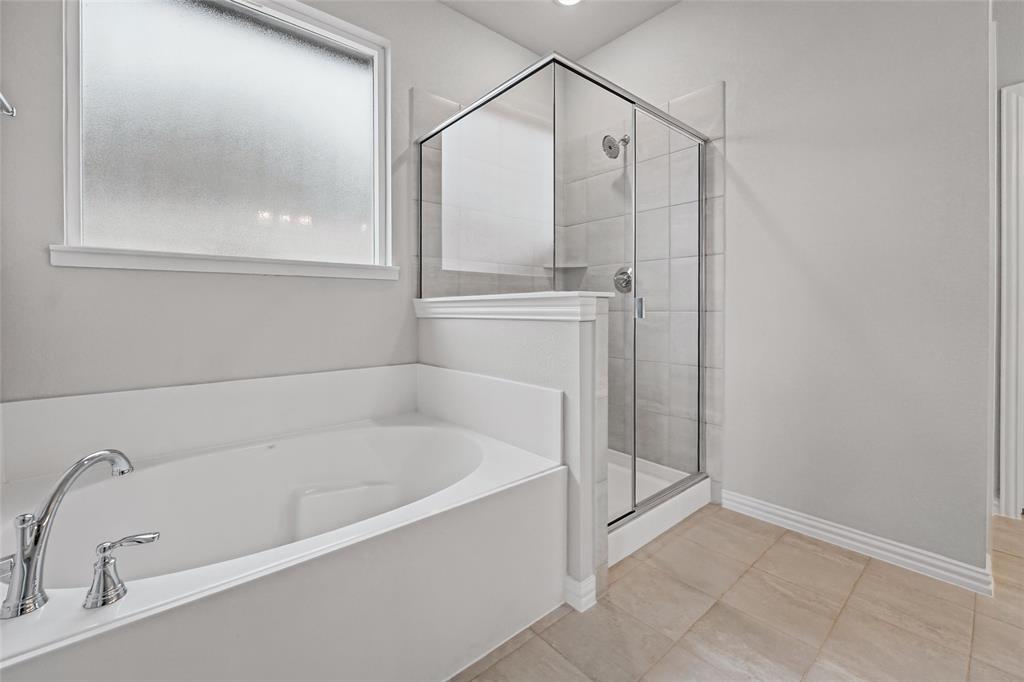 1205 Colca Drive Springtown, TX 76082 - Photo 20 of 37 Built-in soaking tub with chrome fixtures, enclosed glass shower with tiled walls, frosted window, and neutral tile flooring