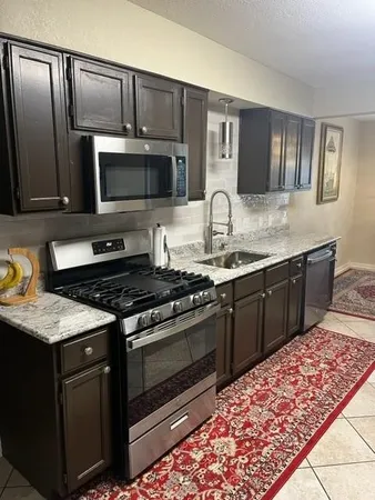 a kitchen with stainless steel appliances granite countertop a stove microwave and sink