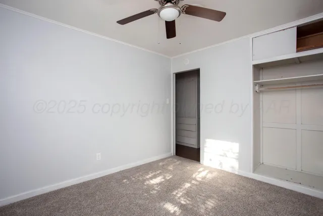 an empty room with ceiling fan and window