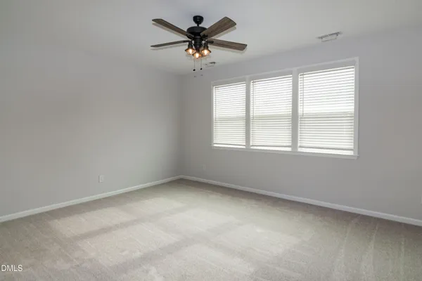 an empty room with a window and a fan