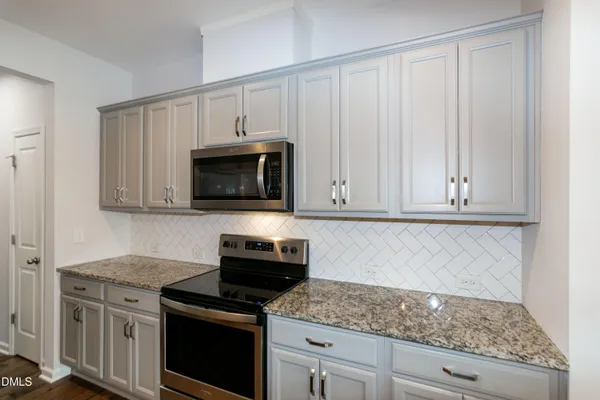 a kitchen with granite countertop white cabinets and a stove top oven