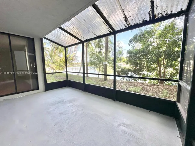 a view of an empty room with wooden floor and windows