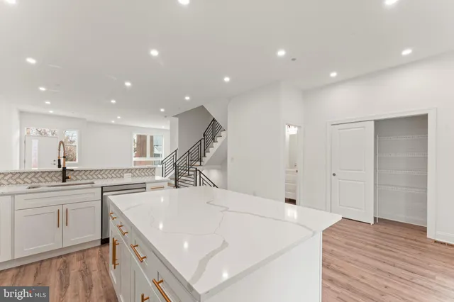 a large white kitchen with wooden floor and a sink
