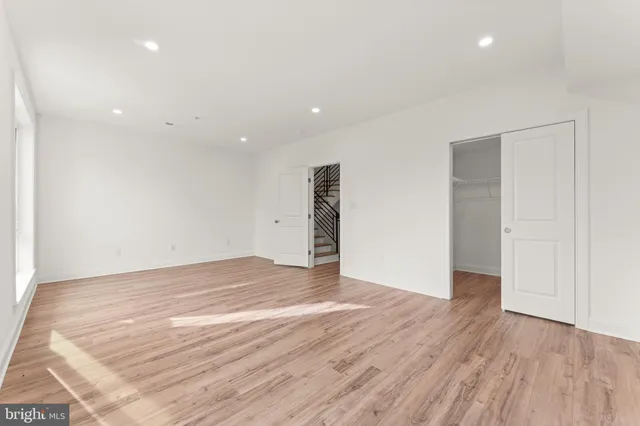 a view of an empty room with wooden floor and closet