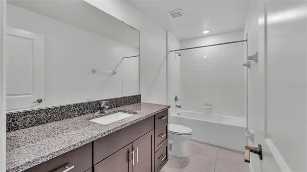 a bathroom with a granite countertop sink a toilet and shower