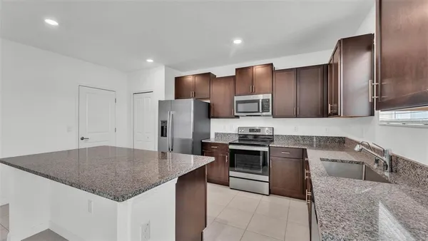 a kitchen with stainless steel appliances granite countertop a sink refrigerator and stove