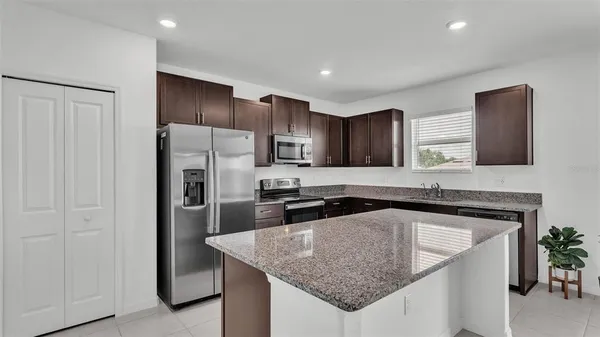 a kitchen with granite countertop stainless steel appliances a refrigerator a sink a stove a microwave and island