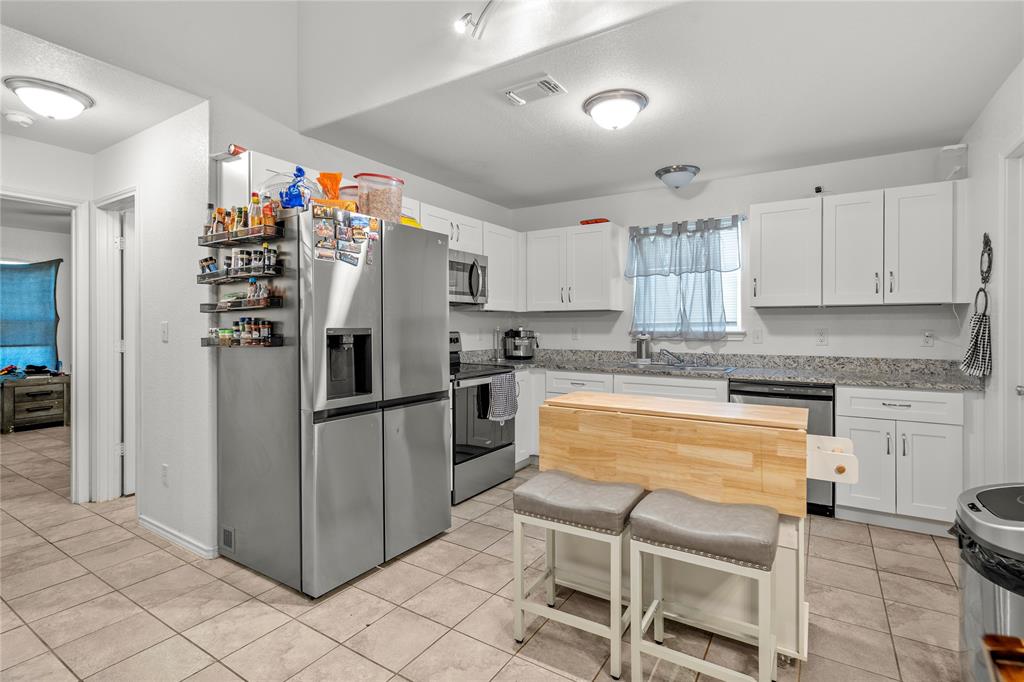420 Whitney Court Rio Vista, TX 76093 - Photo 9 of 25 a kitchen with granite countertop a refrigerator stove top oven and sink