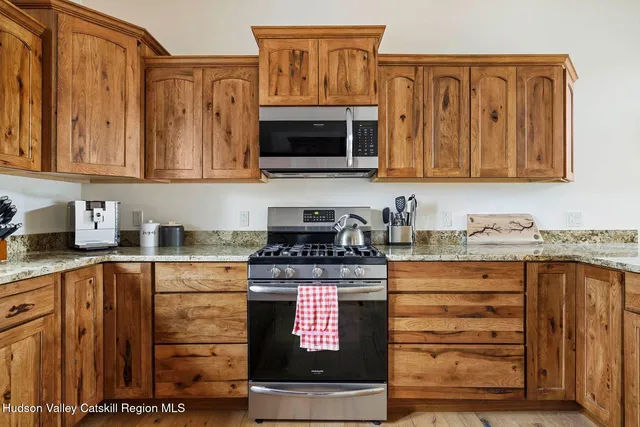 a kitchen with granite countertop a sink cabinets stainless steel appliances and a window