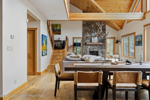 a view of a dining room and livingroom with furniture wooden floor a rug a fireplace and a chandelier