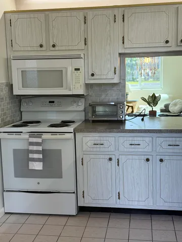 a kitchen with white cabinets a refrigerator a sink and white cabinets
