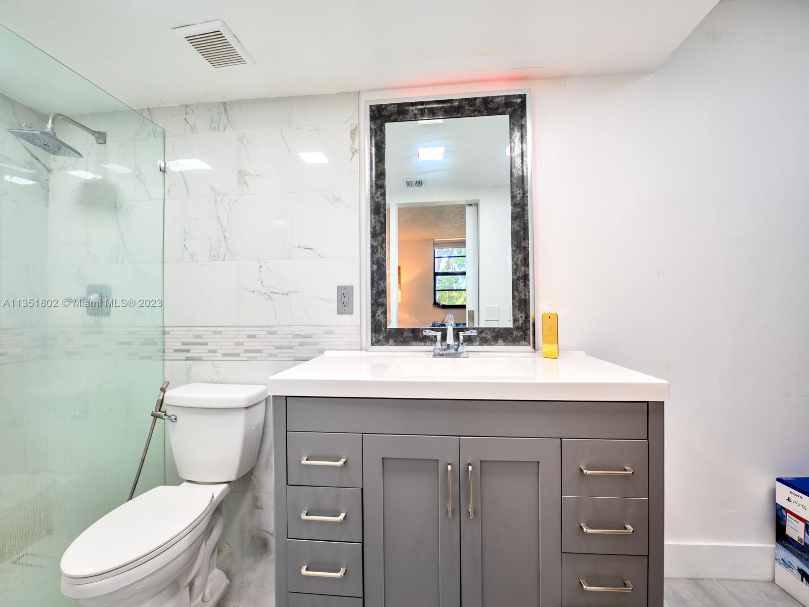 10865 Southwest 112th Avenue, Unit 209 Miami, FL 33176 - Photo 22 of 29 a bathroom with a granite countertop toilet sink and mirror