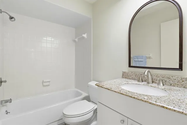 a bathroom with a granite countertop sink a toilet and a mirror