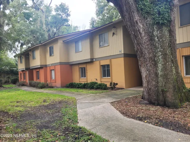 a view of a yard in front of a house with large tree