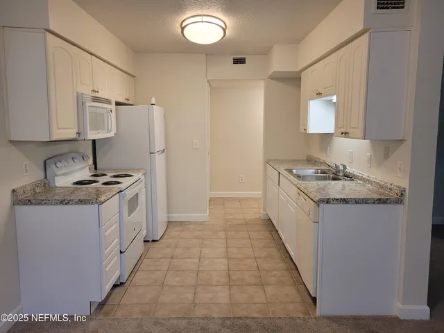 a kitchen with granite countertop a sink stove and cabinets