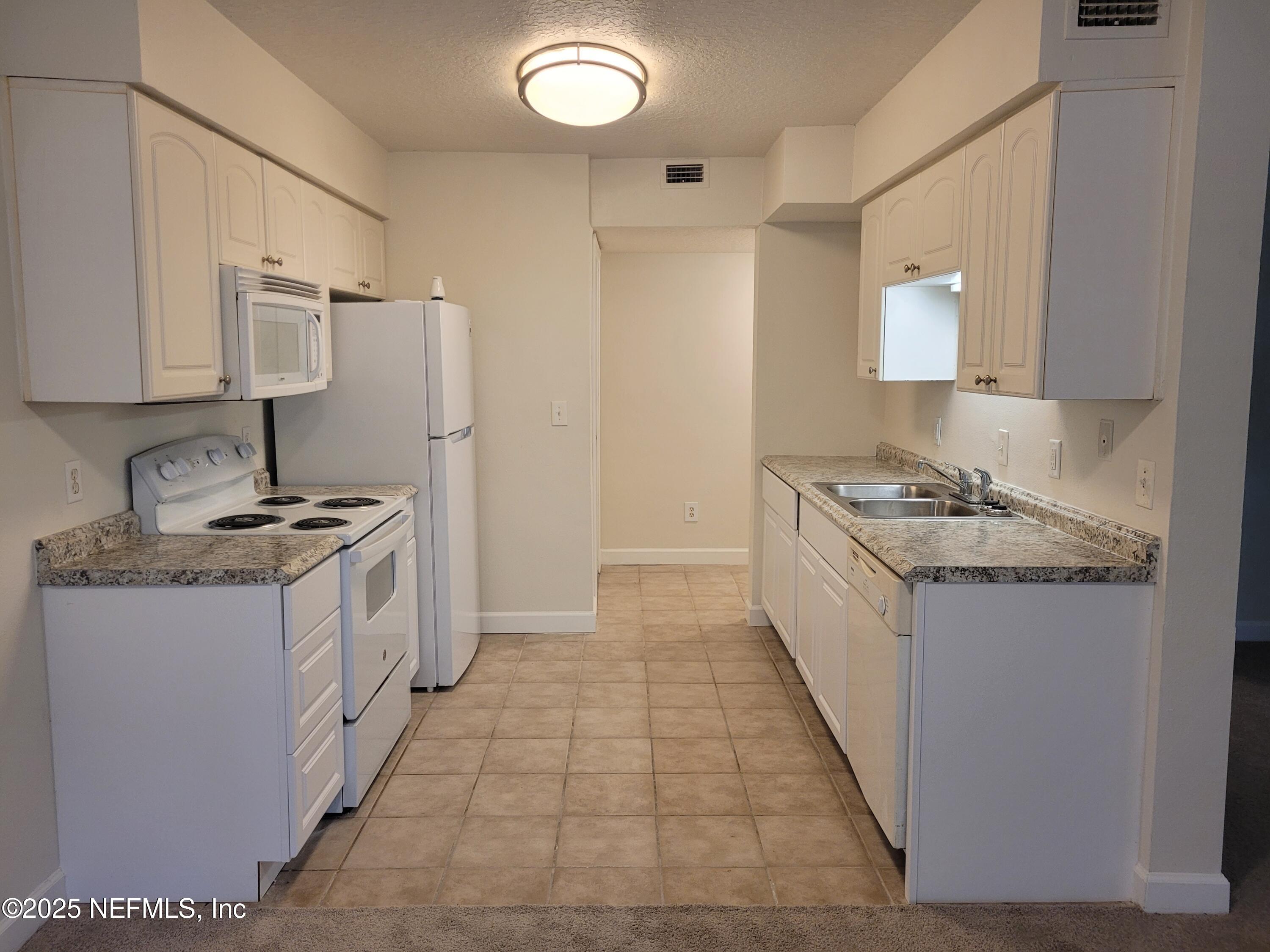 1800 Park Avenue, Unit 339 Orange Park, FL 32073 - Photo 2 of 14 a kitchen with granite countertop a sink stove and cabinets