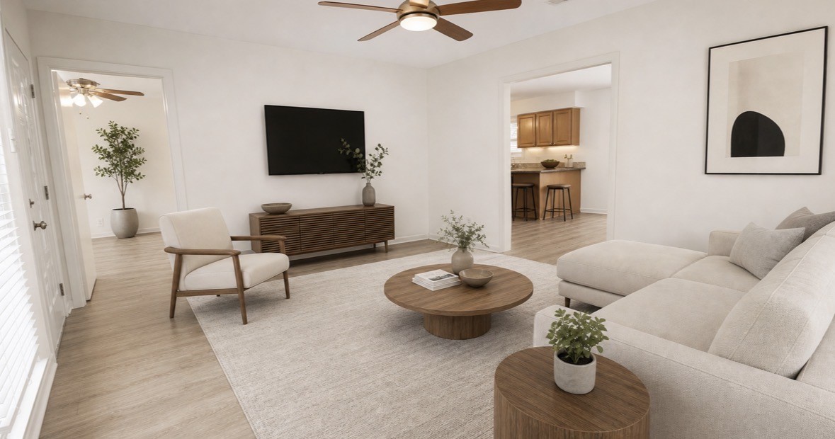 322 Broad Ripple Drive Houston, TX 77336 - Photo 5 of 16 This photo showcases a modern, airy living room with neutral tones. It features a cozy sectional sofa, a sleek TV mounted on the wall, and contemporary decor. The room flows into a kitchen with wooden cabinets and bar seating, connected by open doorways. Natural light fills the space, highlighting the warm wood flooring.