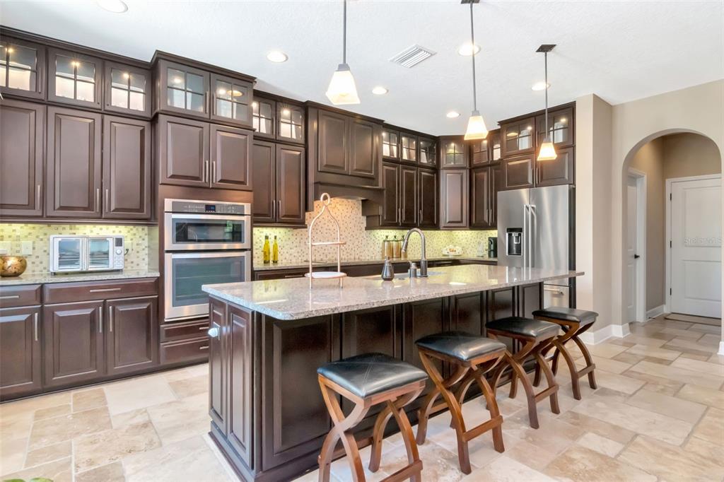 4527 Scarlet Loop Wesley Chapel, FL 33544 - Photo 21 of 57 a kitchen with granite countertop a table chairs stainless steel appliances and cabinets